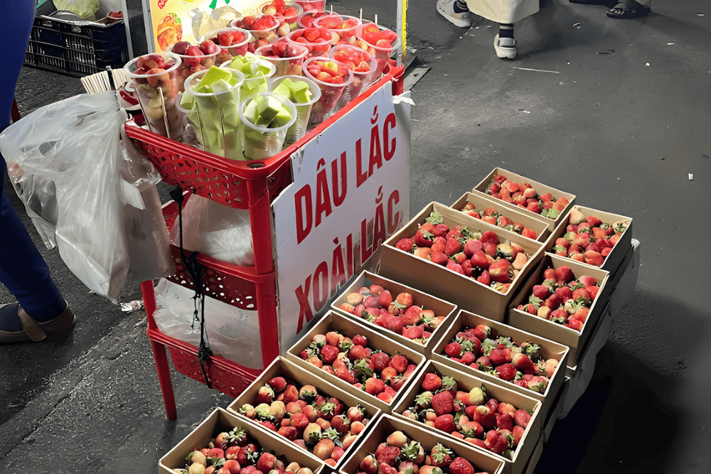 Dọc hai b&ecirc;n đường v&agrave;o chợ, du kh&aacute;ch dễ d&agrave;ng bắt gặp những xe h&agrave;ng b&agrave;y biện những ly d&acirc;u lắc đỏ rực, hấp dẫn (Nguồn: Clara GIRARD - Google Map)